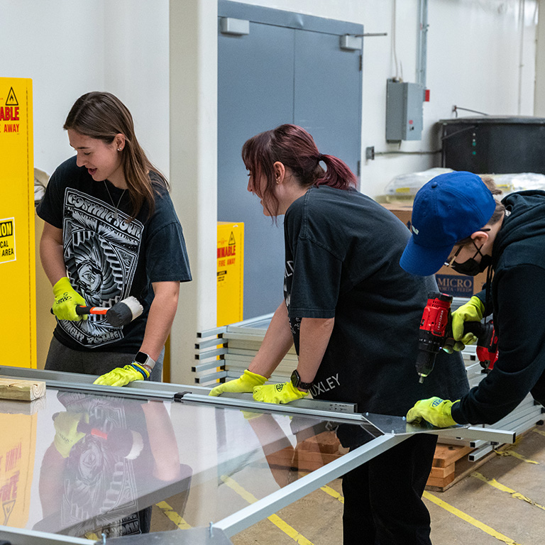 Students working on a sheet of plexiglass