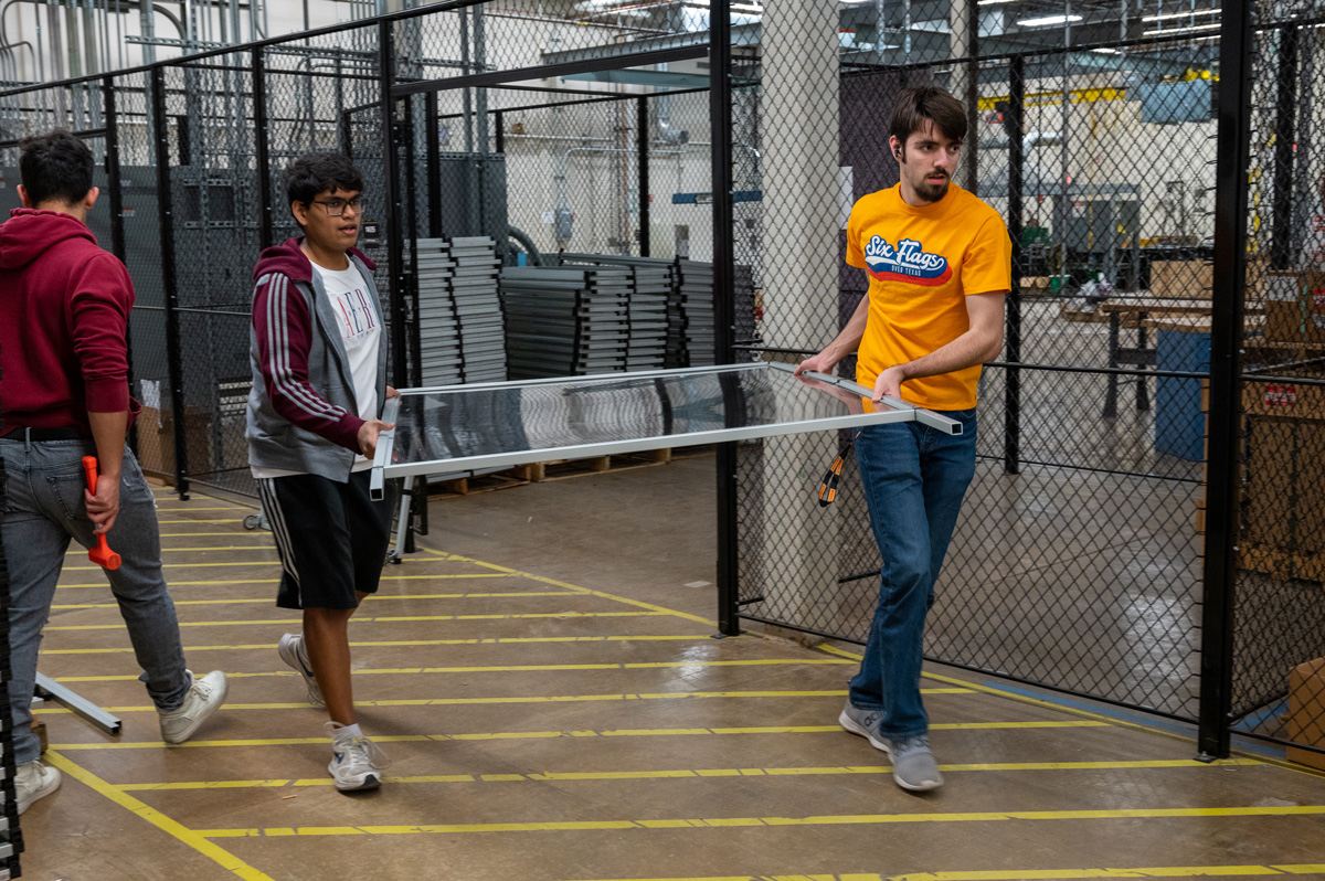 Students carrying a sheet of plexiglass