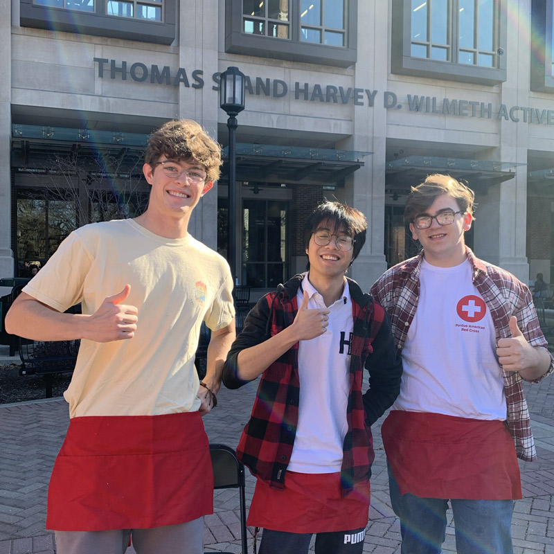 Red Cross members holding a thumbs up in-front of the wall