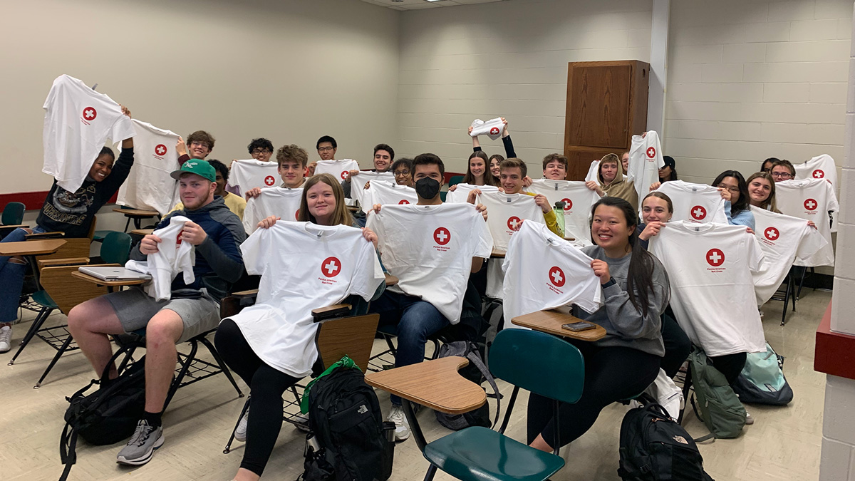 Red Cross club member all holding up their club shirts 