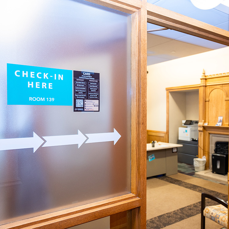 Doorway to CARE office with a sign reading "Check In Here, room 139".